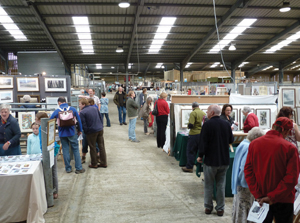 People looking at lots of art displays in a massive barn